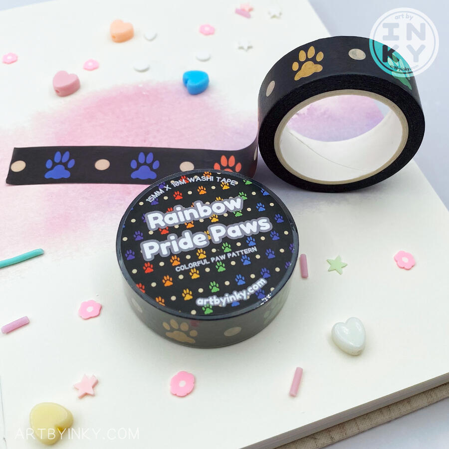 Pride Paws Washi Tape Opened and unopened rainbow pride paws pattern washi tape rolls laid out on a hardcover journal.